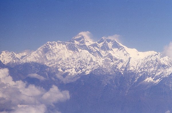 An aerial view of the Himalayas with windswept Mount Everest in the center. The mountain is located on the Nepal-China border and is shared by both countries. Mount Everest is the highest point on Earth above sea level at 8,849 m (29,025 ft). The mountain was named after Sir George Everest, a British surveyor and geographer who served as the Surveyor General of India from 1830-1843 An aerial view of the Himalayas with windswept Mount Everest in the center. The mountain is located on the Nepal-China border and is shared by both countries. Mount Everest is the highest point on Earth above sea level at 8,849 m (29,025 ft). The mountain was named after Sir George Everest, a British surveyor and geographer who served as the Surveyor General of India from 1830-1843