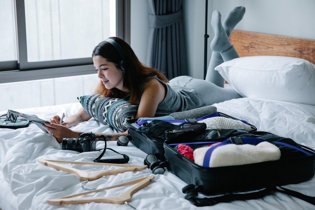 A Woman Using Headphones while Writing on the Notebook
