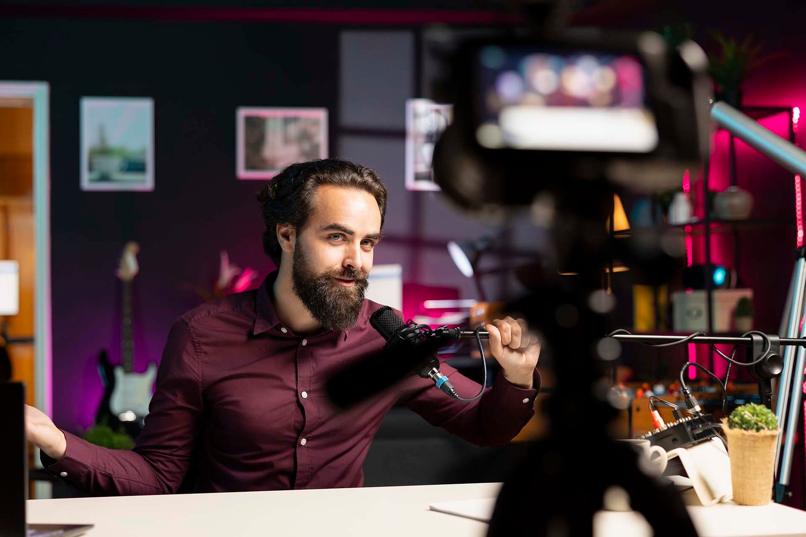 Influencer in rgb lit studio preparing microphone for vlog shooting